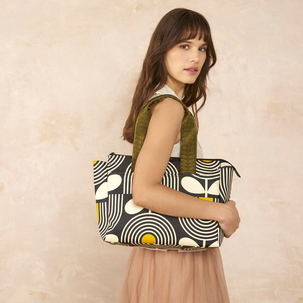 Model wearing the Walker Tote Bag in Giant Striped Tulip Noir pattern by Orla Kiely