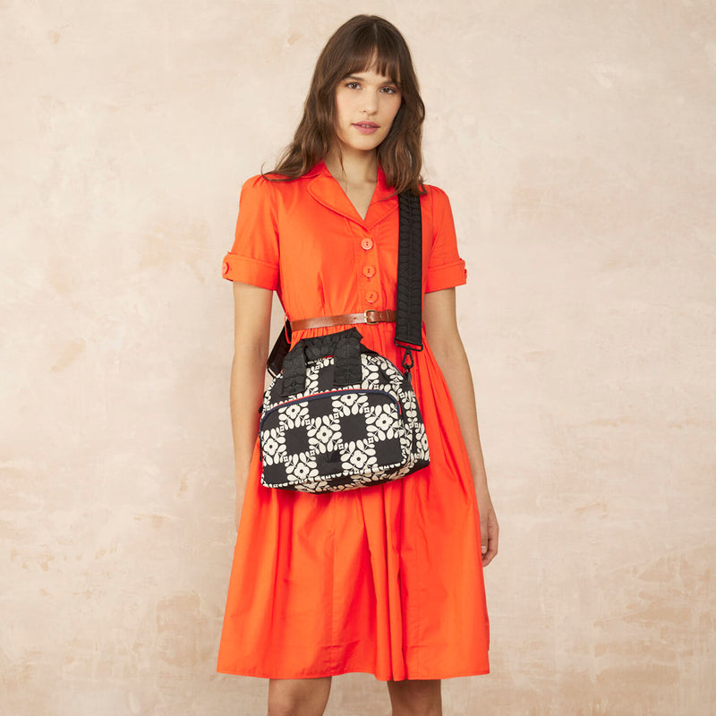 Model wearing the Radial Handbag in Lattice Flower Tile Onyx pattern by Orla Kiely