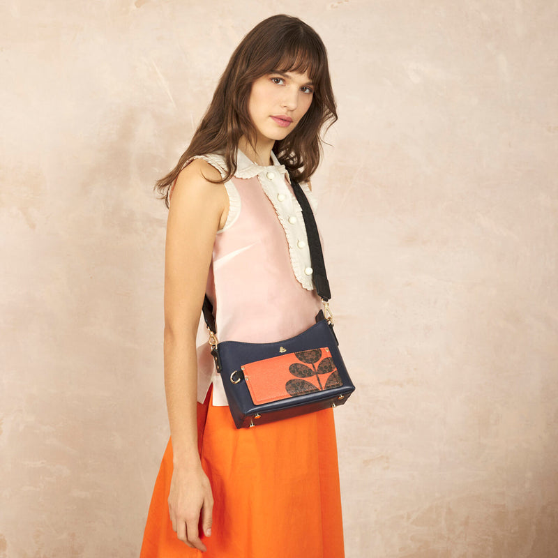 Model wearing the Carrymin Crossbody Bag in Navy Puzzle Flower Emblem pattern by Orla Kiely