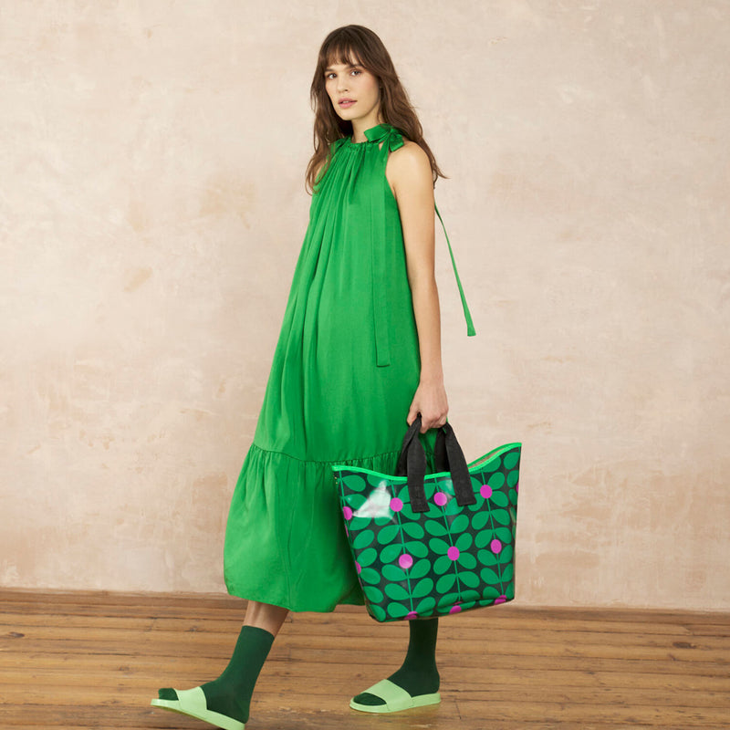 Model wearing the Carryall Large Tote Bag in Sixties Stem Emerald pattern by Orla Kiely