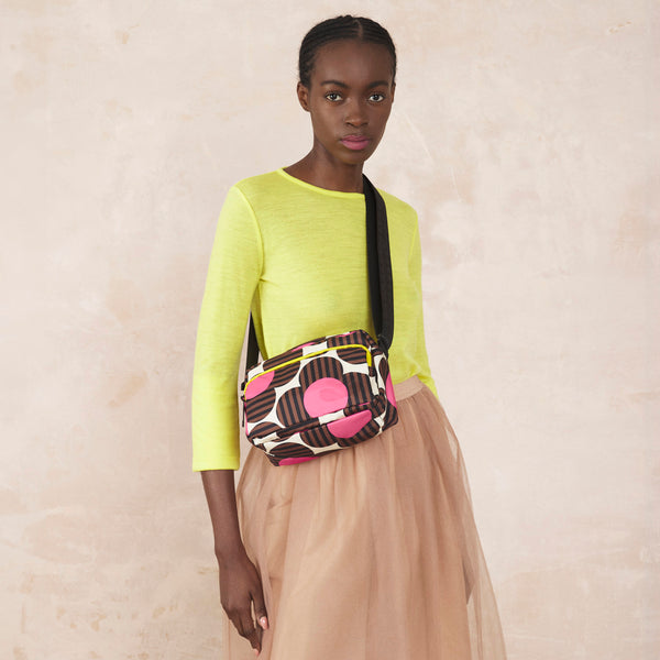 Model wearing the Angle Camera Bag in Striped Flower Azalea pattern by Orla Kiely